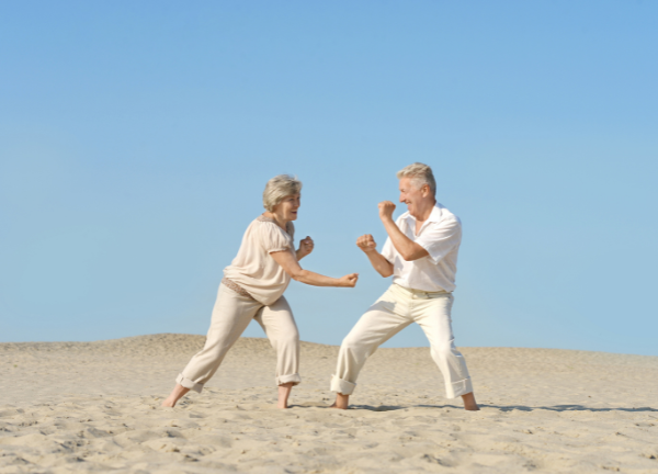 Aktives Seniorenpaar bewegt sich am Strand – Beckenboden Training für mehr Mobilität und Sicherheit