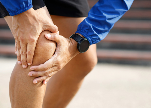 Sportler hält schmerzendes Knie – Schutz vor Verletzungen und Regeneration durch Beckenbodentraining