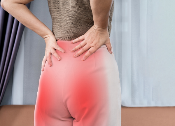 Frau hält sich den schmerzenden unteren Rücken – Beckenbodentraining gegen Rückenschmerzen und Beschwerden